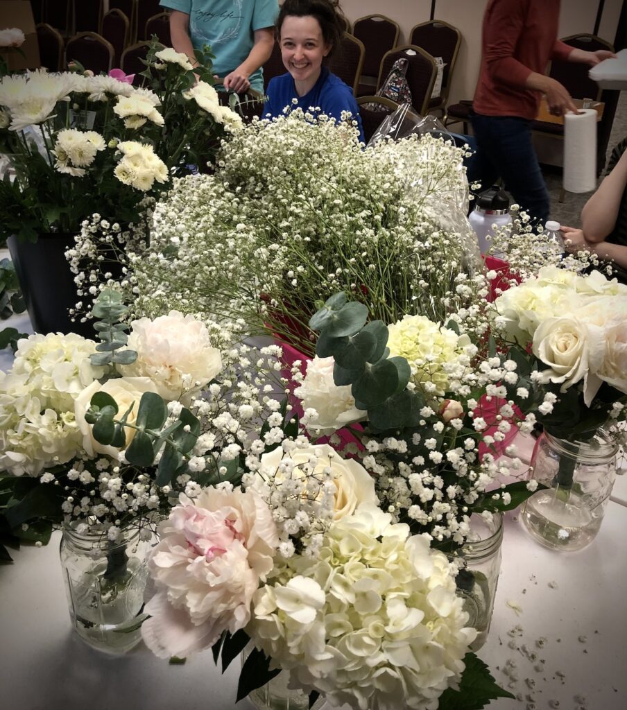 white wedding flower bouquets with bride smiling in the background